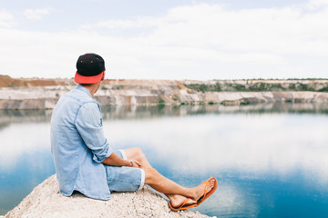 Fototapeta premium Portrait of a man sitting on a rock, travel around the island, a tourist on vacation