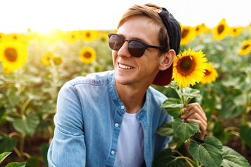 Portrait of a man in a cap and glasses, on the background of a field with sunflowers