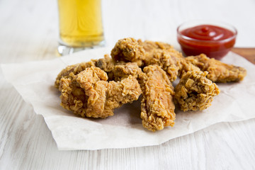 Chicken wings with ketchup, cold beer on a white wooden table, closeup.