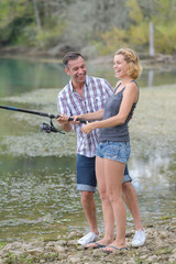 happy couple fishing by the pond