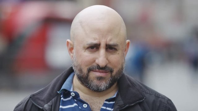 Portrait of bald male with a beard looking to camera before smiling