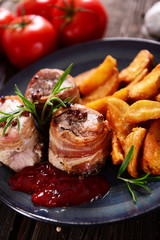 Meat chunks wrapped with bacon served with potato wedges