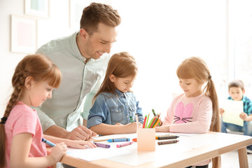 Cute little children with teacher in classroom at school