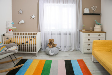Cozy baby room interior with crib and rocking chair