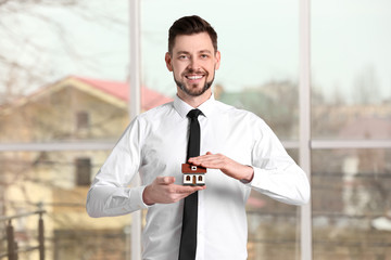 Real estate agent holding house model, indoors