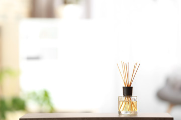 Fototapeta na wymiar Aromatic reed air freshener on table against blurred background