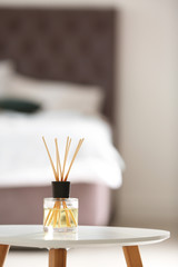 Aromatic reed air freshener on table against blurred background