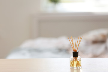 Fototapeta premium Aromatic reed air freshener on table against blurred background