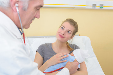 pediatrician doctor talks to young mother of newborn baby