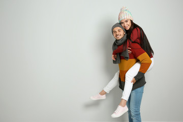 Young happy couple in warm clothes on light background. Christmas celebration