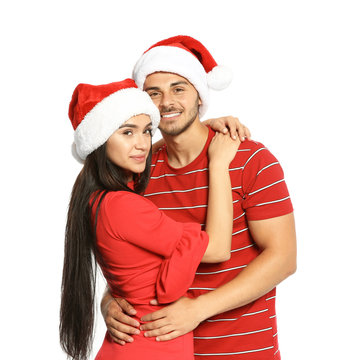 Young happy couple with Santa hats on white background. Christmas celebration