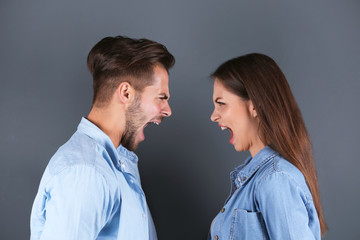 Young couple having argument on grey background. Relationship problems