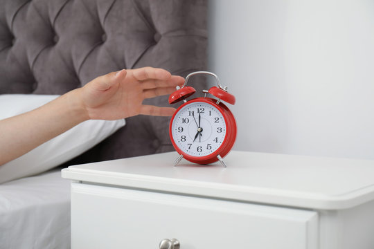 Man turning off alarm clock in bedroom