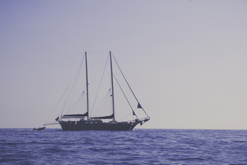 Vintage background of sailing boat on plain ocean and sky