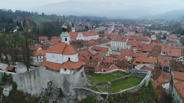 Flying past church and strategic defense walls towards historic city center of Kamnik in Slovenia