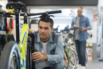happy smiling man choosing new sport bike in store - obrazy, fototapety, plakaty