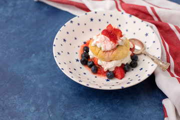 Homemade Strawberry and Blueberry Shortcake in White Bowl with Blue Stars; Red and White Striped Towel; Blue Background