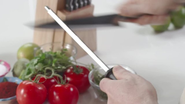 Chef using steel to sharpen large kitchen knife