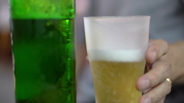 Hand taking frosted beer glass to drink