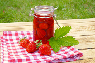 strawberry jam in transparent glass jar on a wooden background. Berry season. strawberry crop	