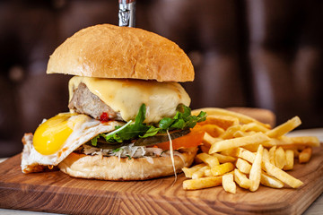 Concept of street food. American burger with a juicy meat patty, salad, tomato and poached egg, with a knife for a burger. Copy space