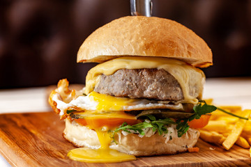 Concept of street food. American burger with a juicy meat patty, salad, tomato and poached egg, with a knife for a burger. Copy space
