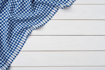 Blue checkered tablecloth on an old wooden table. Close up