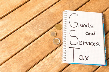 Goods and services and tax . GST inscription in Notepad on wooden background .