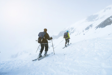 Two men skiing together on the snow mountains on a foggy day.