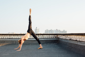 Young and graceful ballerina performing on roof of city building