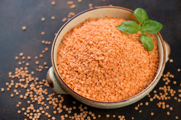 Uncooked red lentils in a bowl, studio shot on a brown metal background, selective focus