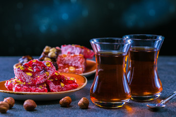 Turkish tea in traditional glass and plate with rahat lokum. Istanbul cafe with oriental culture of the street food.Evening time.