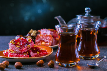 Turkish tea in traditional glass and plate with rahat lokum. Istanbul cafe with oriental culture of the street food.Evening time.
