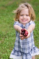 little girl with a cherry in her hands in the forest