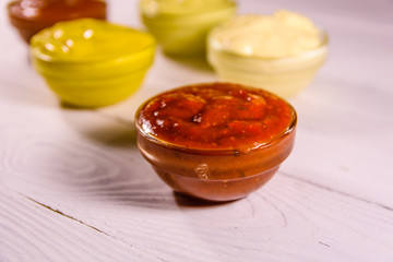 Different sauces in glass bowls on wooden table