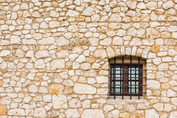 Fototapeta na wymiar A small window of a dungeon with a lattice and a stone wall with space