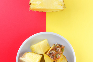 Pieces of pineapple on a white plate, chopped pineapple on a red yellow background, a salad of tropical fruits for breakfast, vegetarian food pop art