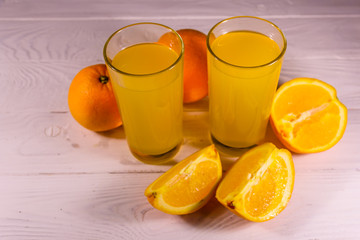 Oranges and glasses with orange juice on a wooden table