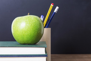 concept of back to school with apple, books, pens and blackboard