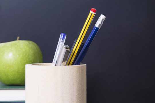 concept of back to school with apple, books, pens and blackboard