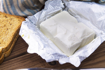 block of butter and slices of bread on wooden board