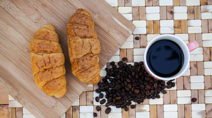 cup of coffee and croissants on wooden background