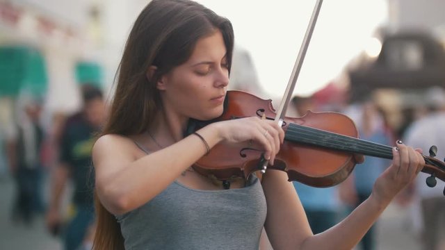 Young woman playing a violin at the pedestrian street