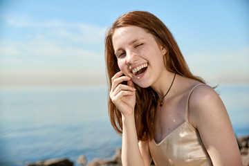 Fototapeta na wymiar Open closeup portrait of young beautiful happy smiling redhead girl, long curly hair, no makeup. 