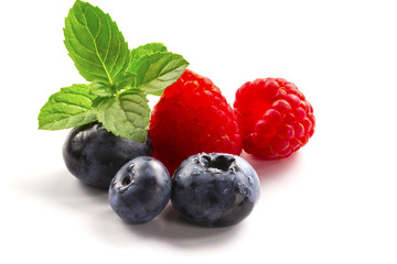 Close-up arrangement mixed, assorted berries including blackberries, strawberry, blueberry, raspberries and fresh leaf on white