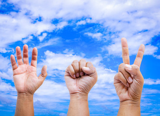Rock  Paper  and Scissors on sky background. Hand young man are playing rock paper scissors.