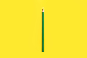 new single green pencil with a sharp lead lying on a yellow background. concept of artists nececcary tools