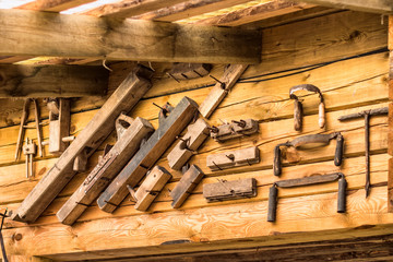 Old rusty tools for carpenter at the wood wall of the house. Plane hand, jointer hand, drill hand and others