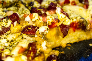Obraz na płótnie Canvas homemade pizza with peppers, plums, ham, sausage, cheese and spices, closeup