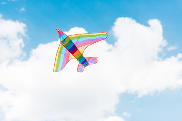 colorful kite flying in blue sky with clouds